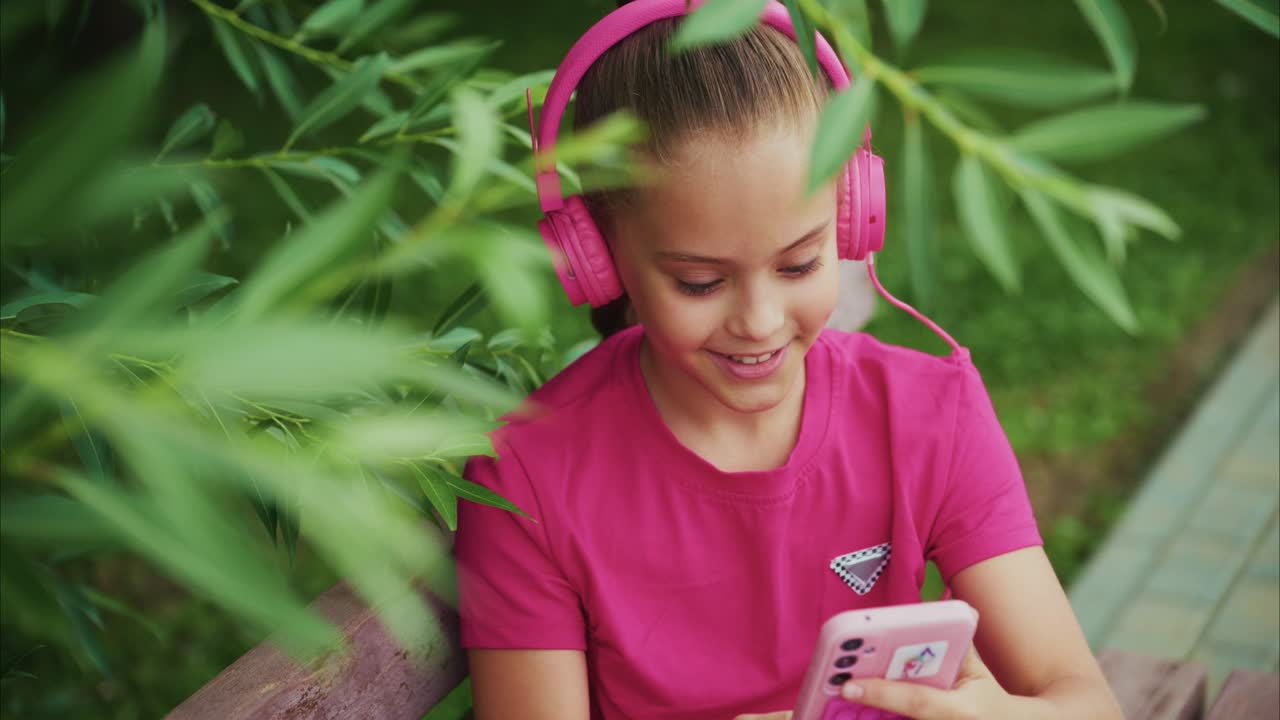 A Young Girl Enjoys Music and Technology with Pink Headphones While Relaxing in Nature, Captured from Two Different Angles in a Serene Outdoor Setting