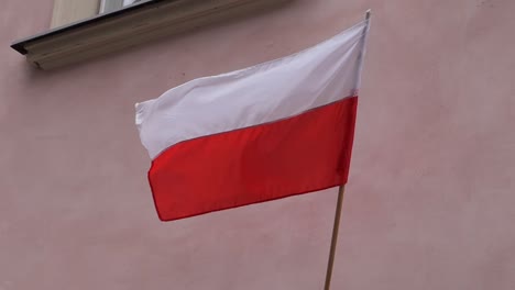 bandera polaca ondeando en un mástil en una pared de la casa en el viento