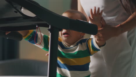 child learning to use a treadmill with mother's help