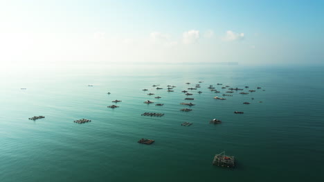 many floating cages for fish and lobster farming at awang bay fishing harbour, sky touching sea horizonlombok, mertak, indonesia, aerial shot