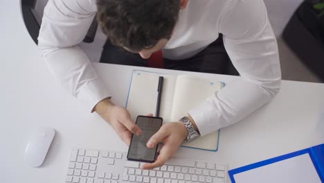 Businessman-looking-at-drawn-architectural-projects-on-his-phone.