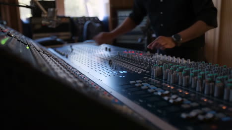 a person working on an audio mixing console in a recording studio