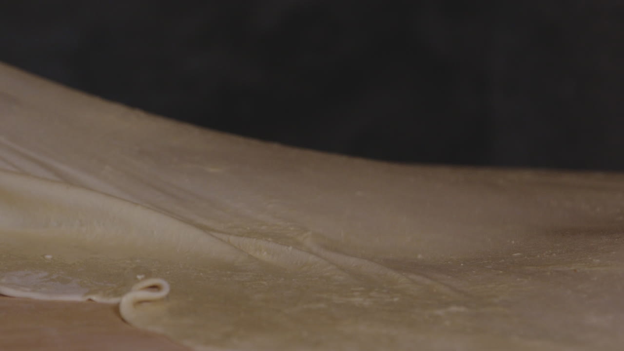Donna che stende l'impasto piatto e sottile per i Khinkali, ravioli georgiani - primo piano