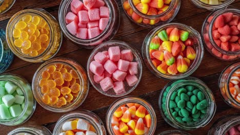 colorful assorted candy in glass jars on wooden table