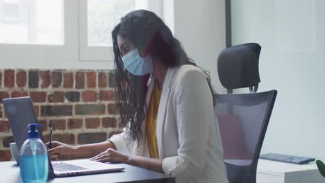 mujer con máscara facial tomando notas en la oficina