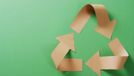 primer plano del símbolo de reciclaje de flechas de papel sobre fondo verde, con espacio para copiar