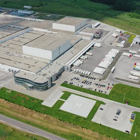 white factory on field. modern industrial plant with parking spaces for trucks and cars among green nature. aerial view.