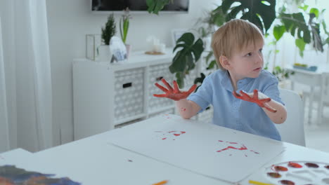 little child with hands painted in colorful paints ready for hand prints