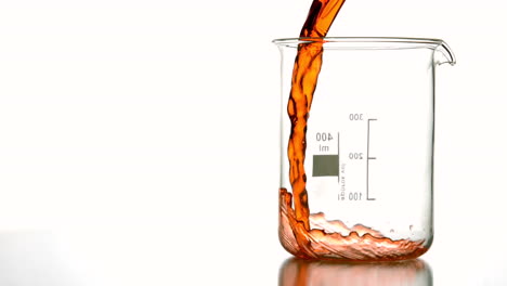 orange liquid pouring into beaker