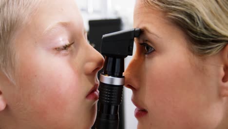 una optometrista examinando a un paciente joven con un oftalmoscopio