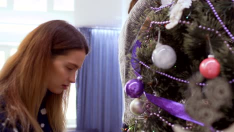 las chicas bonitas decoran el árbol de navidad y se dan un "high-five"