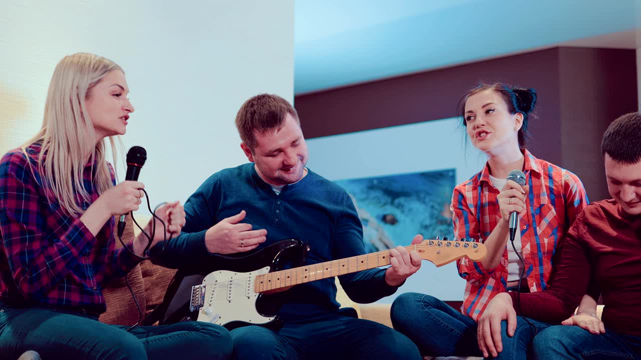 회사 재는 친구들이 마이크로 노래하고 전기 기타를 연주하고, 노래하고 집에서 재미를 느끼고 있습니다.