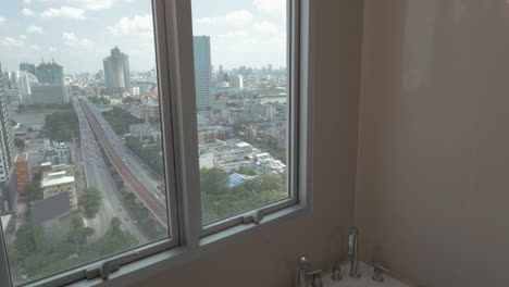 En-La-Ciudad-De-Bangkok,-Tailandia,-Una-Joven-En-Un-Apartamento-Junto-A-La-Ventana-Tomando-Un-Baño