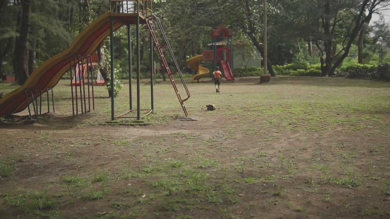 niño enérgico corriendo hacia el tobogán en un parque, goa, india