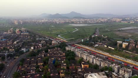 panoramic view on road, train station, and commercial buildings in suburban area of vasai, mumbai - aerial drone shot