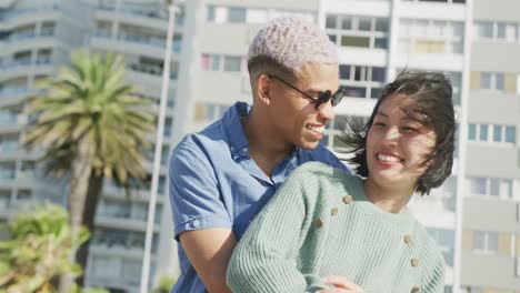 Happy-biracial-couple-embracing-on-promenade,-in-slow-motion