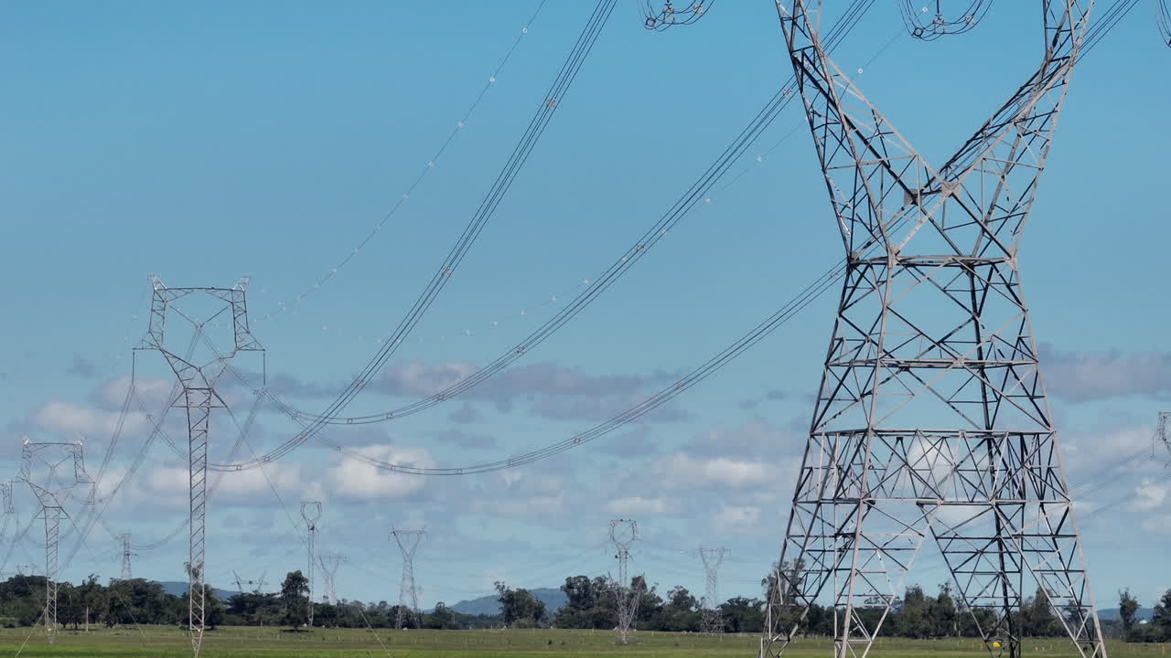 Transmission towers and high voltage power lines span an open landscape, emphasizing large scale grid infrastructure, power distribution and energy network capacity