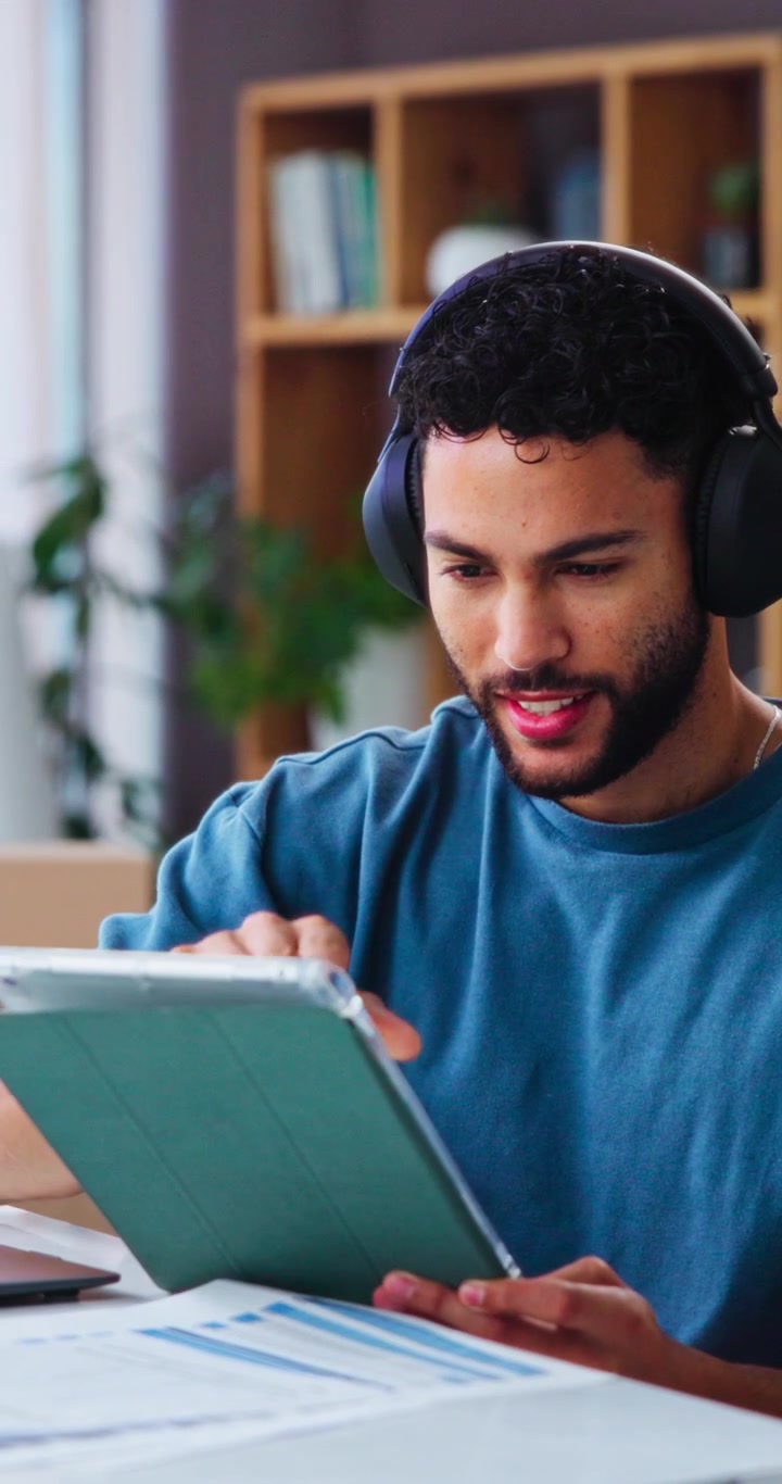 Young Man Using Tablet and Headphones in Home Office