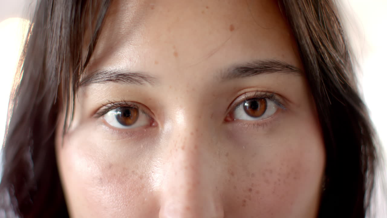 Close-up of woman's eyes with freckles, expressing curiosity and focus