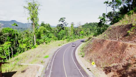 car driving past red house on winding road
