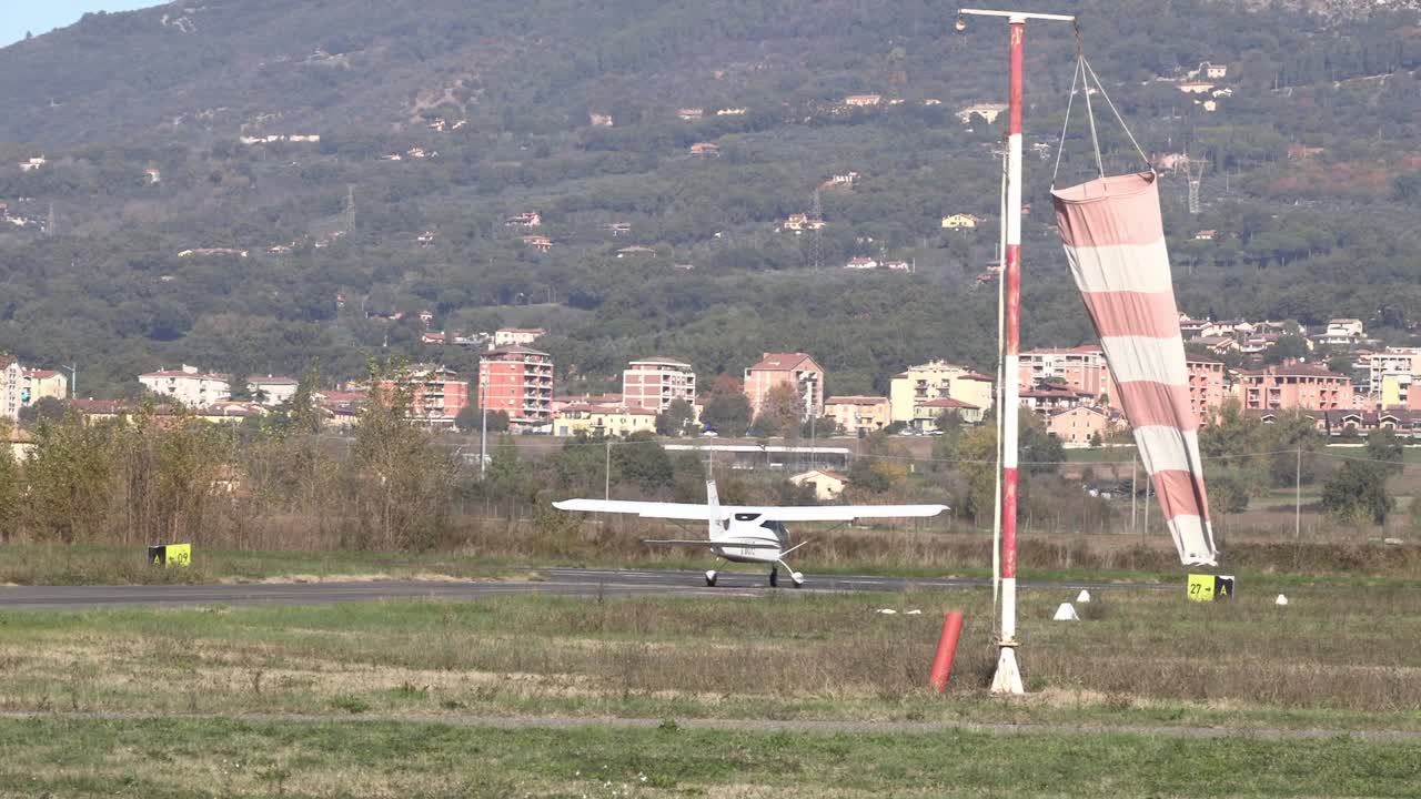 Un piccolo aereo che rulla sulla pista di un aeroporto e si allontana dall'inquadratura