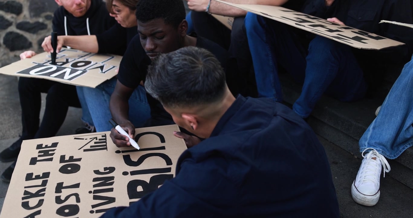 Diverse Group of People Writing Protest Signs for Cost of Living Crisis