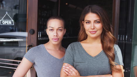 portrait of two female owners of start up coffee shop or restaurant standing in doorway