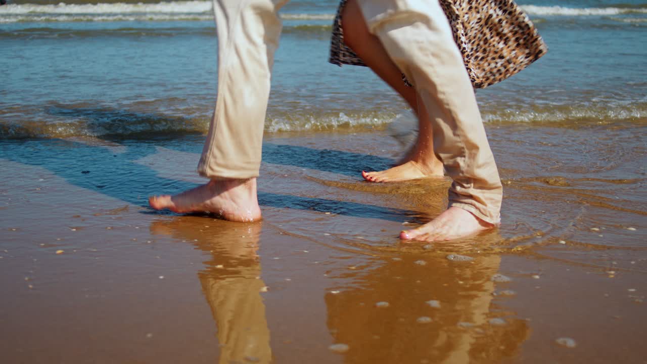 The Feet of a Woman and a Man Stroll Along the Beach in The Netherlands - Tracking Shot