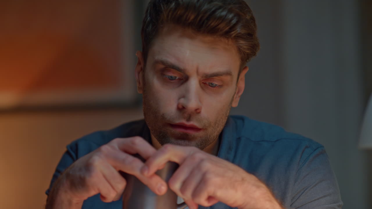 Thoughtful man holding cup thinking in night house closeup. Sad guy pondering