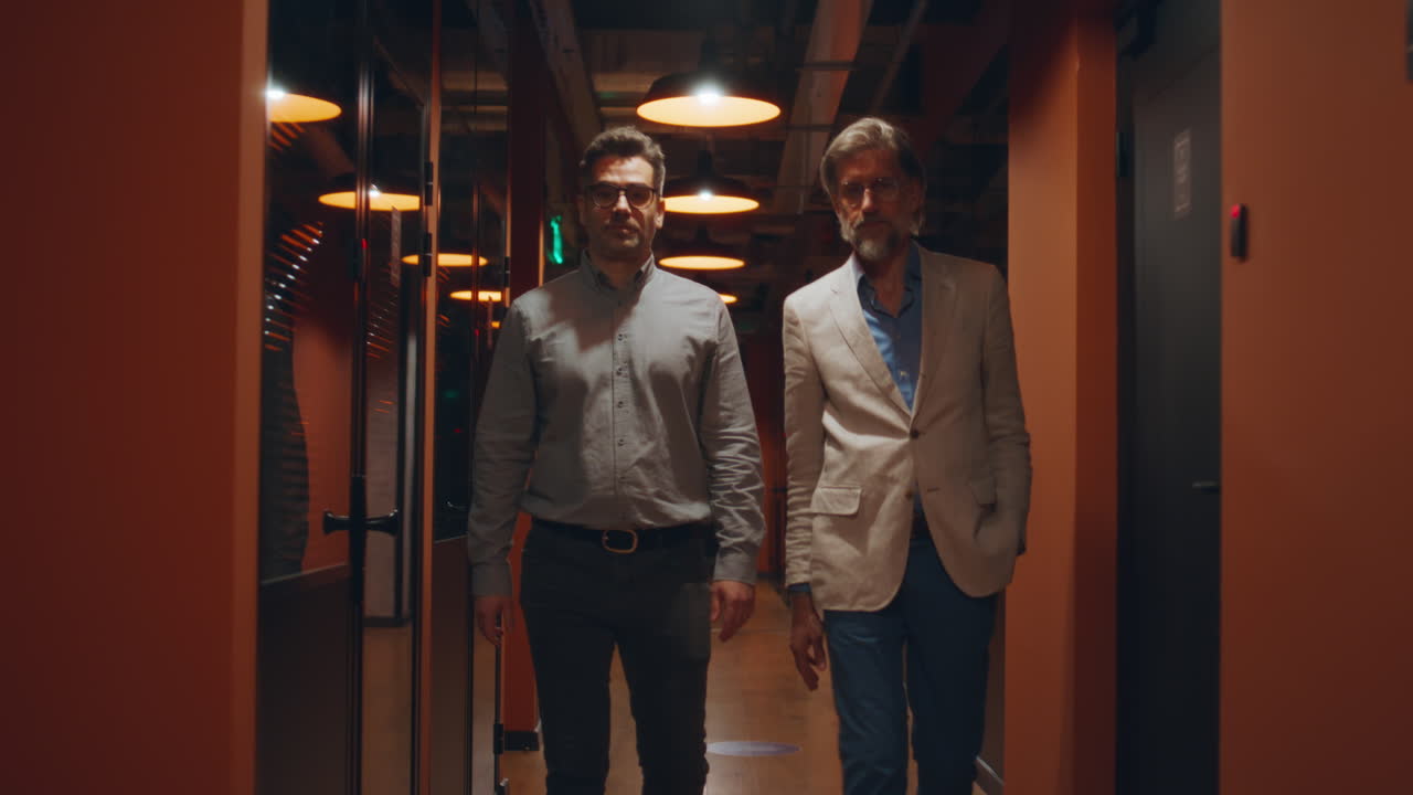 hombres de negocios hablando en el corredor de la oficina por la noche