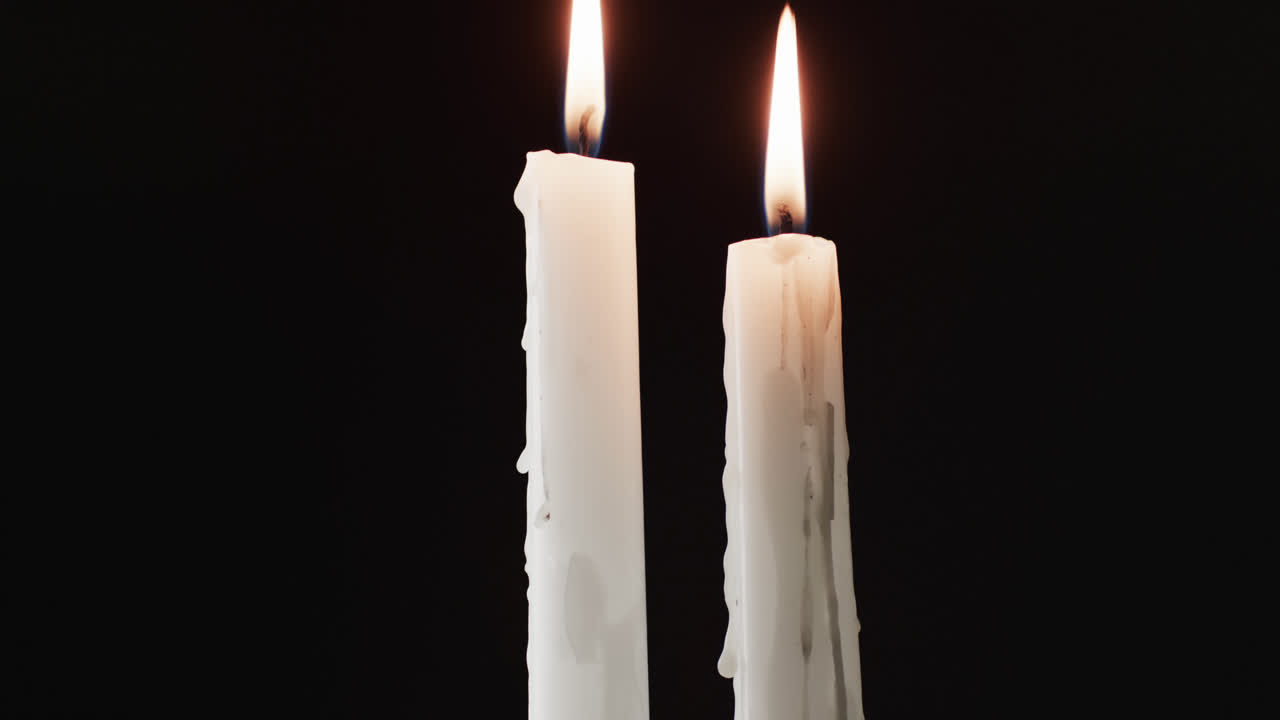 Video di due candele bianche con fiamma bianca e spazio per il testo su sfondo nero