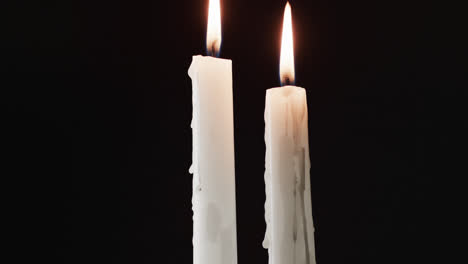 Video-of-two-white-candles-with-white-flame-and-copy-space-on-black-background