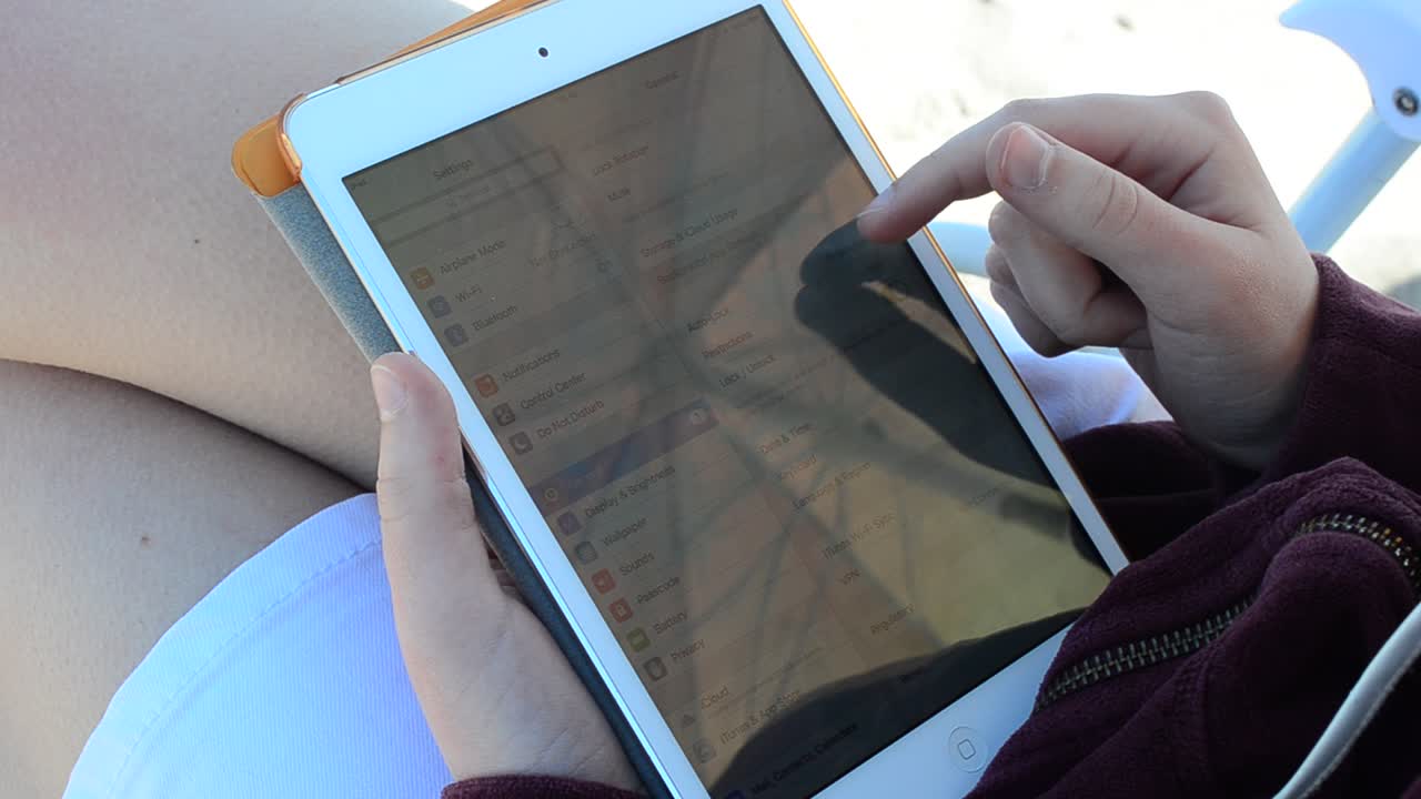 The tablet in the girl's hands on the beach. Work on the tablet. Shooting on the beach
