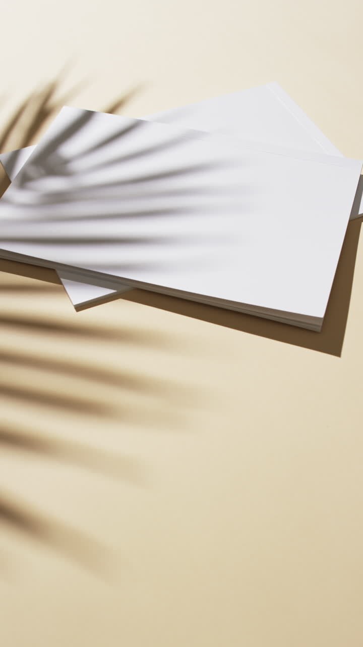 Vertical video of shadow of plant over books with blank pages and copy space on yellow background