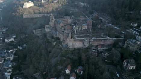 Vista-Aérea-De-Un-Castillo-Gótico-Situado-En-Lo-Alto-De-Una-Colina-De-Un-Pueblo-Remoto-En-Europa