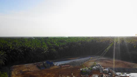 Cinematic-4K-Drone-Footage-of-Onshore-Drilling-Rig-equipment-structure-for-oil-exploration-and-exploitation-in-the-middle-of-jungle-surrounded-by-palm-oil-trees-during-sunset-and-high-oil-price