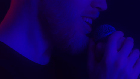 hombre cantando en el micrófono con una vibrante iluminación de neón