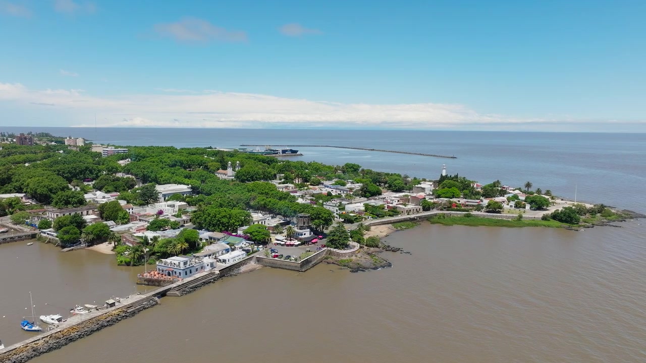 Hidas panoroiva dronekuva Colonia del Sacramentosta, Uruguayssa aurinkoisena päivänä. Historialliset mukulakivikadut ja siirtomaa-ajan arkkitehtuuri. Kirkas sininen taivas