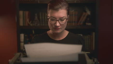 vintage scene of a pretty woman typing on typewriter in front of a book case - dolly shot in