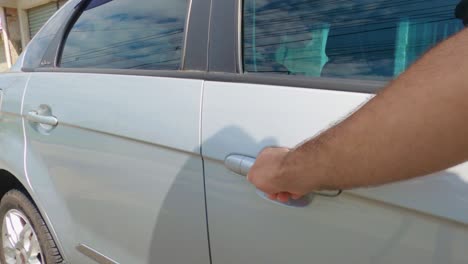 man trying to open a locked car by pulling the handle