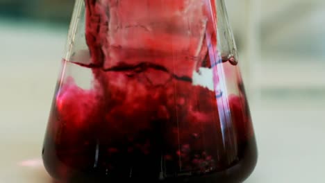 científico vertiendo líquido de tubo de ensayo en un frasco de erlenmeyer