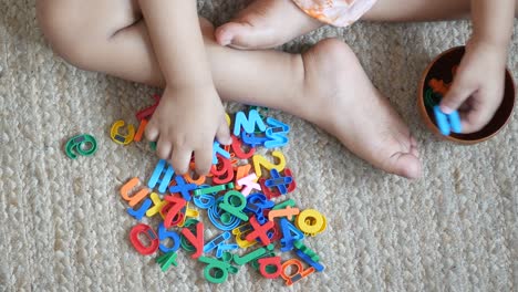 top view of child playing with plastic letter on floor