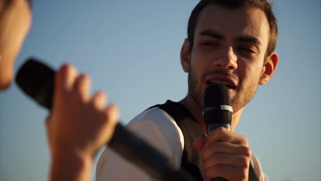 man singing into microphone outdoors