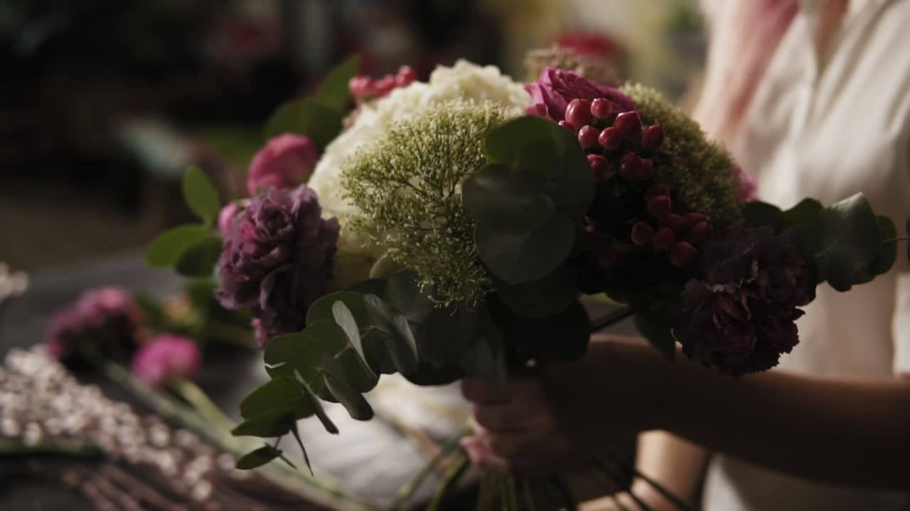 A colorful bouquet of fashionable fluttering flowers in the girl's hands. Muffled light. Close up
