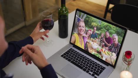 sección media de una mujer afroamericana bebiendo vino mientras hace una videollamada en una computadora portátil en casa