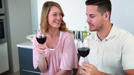una pareja feliz sonriendo a la cámara brindando con vino rojo
