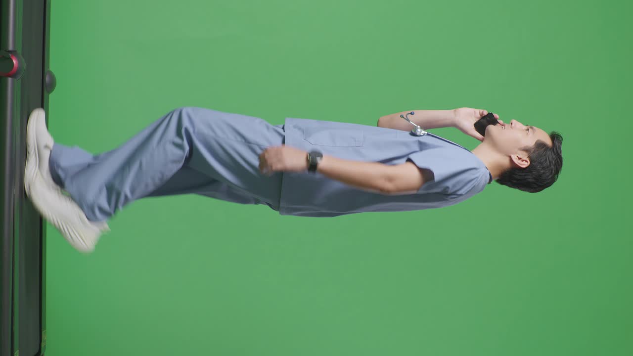 병원에서 녹색 화면 배경에서 는 동안 스마트폰으로 말하는 스테토스코프를 가진 아시아 남성 의사