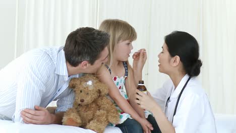 el médico le da jarabe a una niña en el hospital.