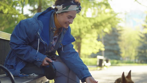 happy woman petting corgi dog in park