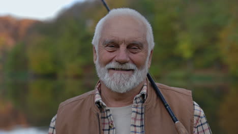 smiling senior man with fishing rod outdoors